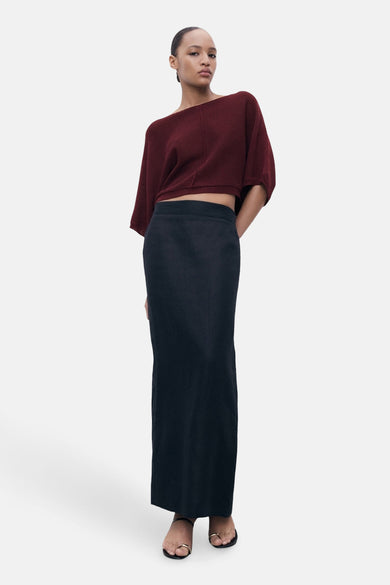 Bordeaux trui met ronde hals van MANGO, gedragen met een lange zwarte rok en sandalen.
