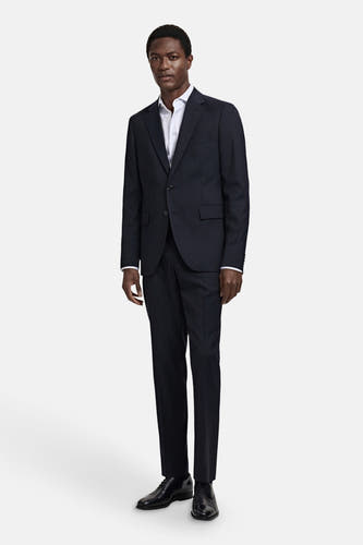 Pantalon de costume bleu MANGO, porté avec un chemisier blanc et des chaussures noires.