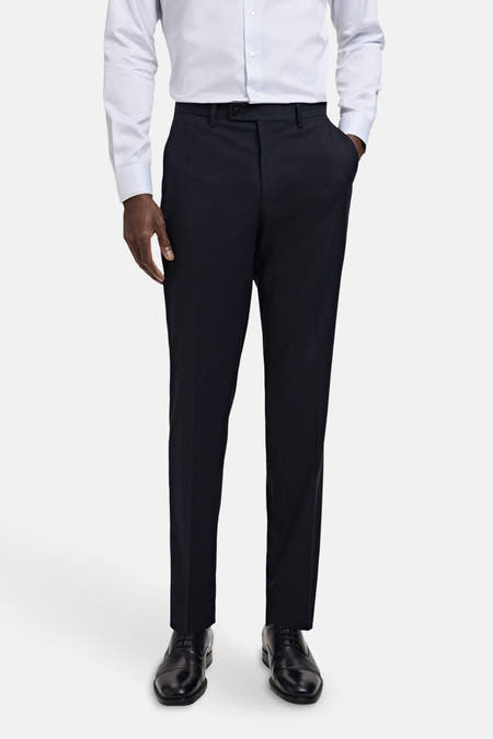Pantalon de costume bleu MANGO, porté avec un chemisier rayé bleu clair et des chaussures en cuir noires.