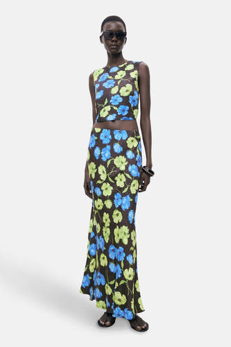 Mouloze sans manches multicolore de MANGO, avec imprimé de fleurs bleues et vertes, associé à une longue jupe et un chapeau de soleil.