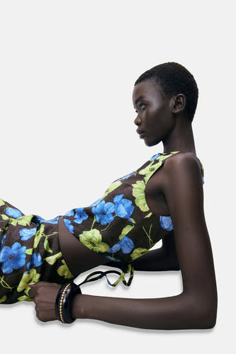 Blouse sans manches multicolore de MANGO, avec des fleurs bleues et des motifs de feuilles vertes, stylée avec un bracelet noir.