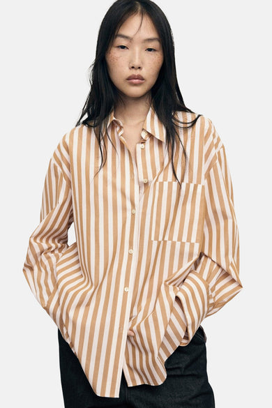 Chemise multicolore à manches longues de MANGO, avec des rayures verticales, portée avec des jeans larges foncés et des talons noirs.