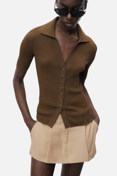 Polo marron à manches courtes de MANGO, avec col boutonné et porté avec un pantalon kaki.