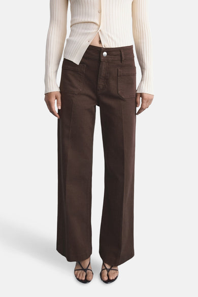 Bruine jeans van MANGO, met wijde pijpen en zakken, gecombineerd met een gebreid vest en sandalen.
