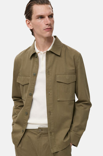 Groen overhemd met lange mouwen van MANGO, met zakken op de borst en gedragen over een wit poloshirt.
