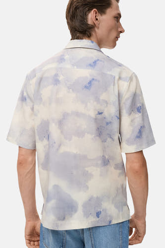 Multikleurig overhemd met korte mouwen van MANGO, met een aquarelpatroon en gedragen met een blauwe jeans.
