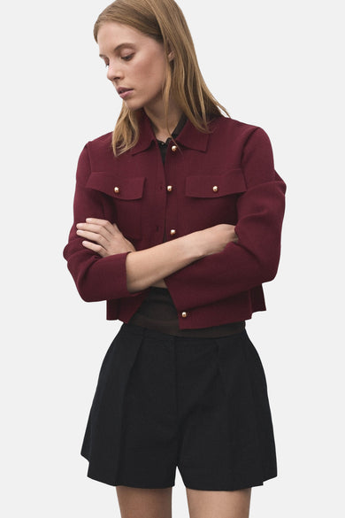 Bordeaux cardigan van MANGO met gouden knopen en opgestikte zakken, gecombineerd met zwarte shorts.