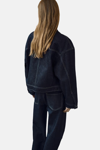Donkerblauwe jeansjas van MANGO, gezien van achteren met bijpassende jeans.