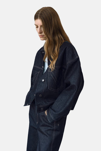 Donkerblauw denim jeansjas van MANGO, met lange mouwen en contraststiksels, gedragen met een lichtblauwe top.