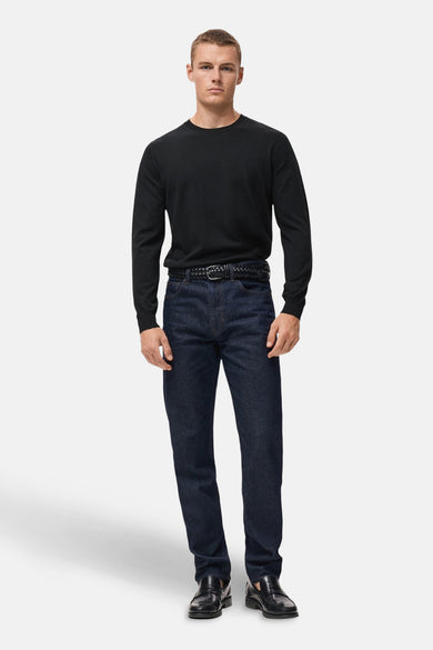 Pull noir avec col rond de MANGO, associé à des jeans foncés et une ceinture en cuir noir ainsi qu'à des chaussures.