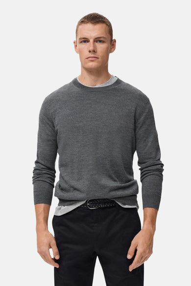 Sweat-shirt gris avec col rond de MANGO, porté sur un t-shirt gris et un pantalon noir à ce.