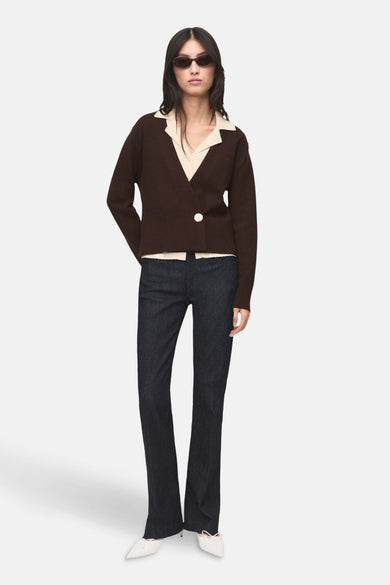 Bruin gilet van MANGO, gecombineerd met een crèmekleurige blouse, donkere spijkerbroek en witte schoenen.