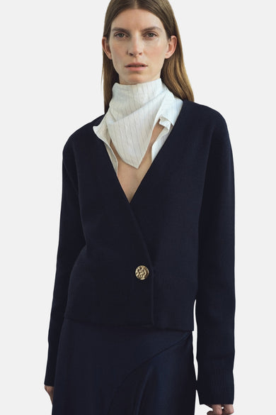 Gilet bleu de MANGO porté sur une chemise à carreaux et une jupe marine.