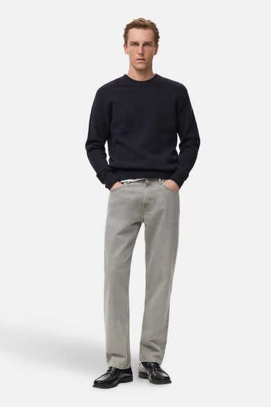 Donkerblauwe trui met ronde hals van MANGO, gedragen met grijze jeans en zwarte schoenen.
