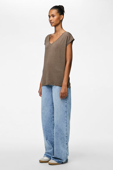 Bruin T-shirt met korte mouwen van PIECES®, gedragen met wijde jeans en sneakers, in zijaanzicht.
