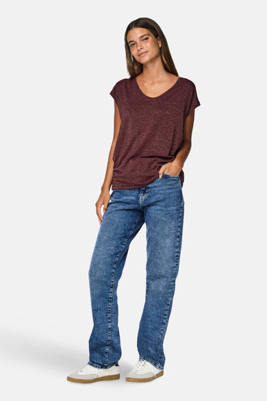 Bordeaux t-shirt met korte mouwen van PIECES®, gecombineerd met blauwe jeans en witte sneakers.