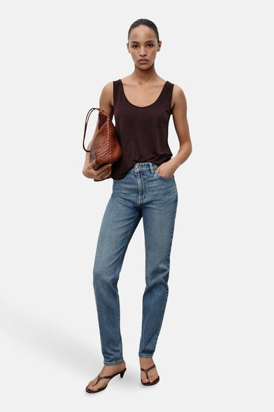 Mid-blue mom jeans van MANGO, gecombineerd met een donkerbruin hemdje en een gevlochten leren tas.