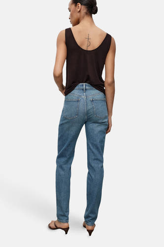 Middenblauwe mom jeans van MANGO, gezien van achteren, gecombineerd met een mouwloze top en bruine hakken.