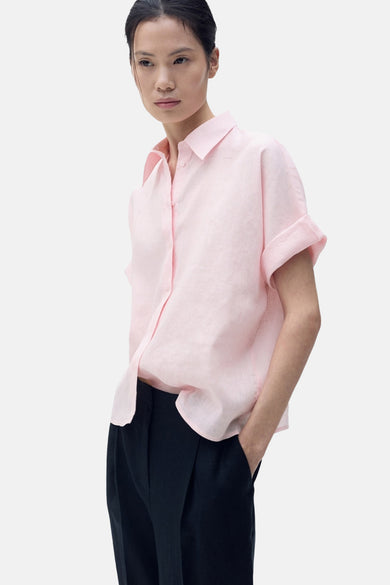 Roze overhemd met korte mouwen van MANGO, losse pasvorm en gedragen met zwarte pantalon.
