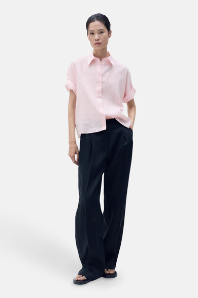 Roze hemd met korte mouwen van MANGO, gecombineerd met een zwarte pantalon en sandalen.