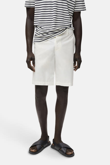 Witte short van MANGO, gecombineerd met een gestreept shirt en zwarte sandalen.