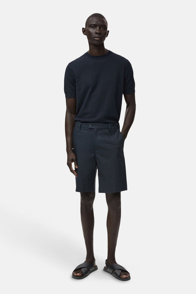 Short bleu de MANGO, porté avec un t-shirt bleu marine et des sandales noires.