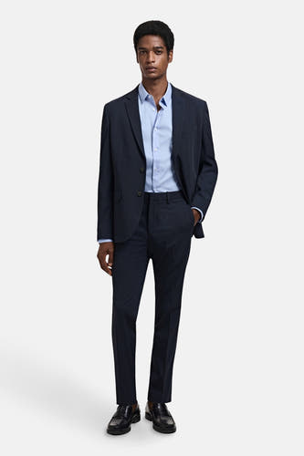 Chemise bleue à manches longues de MANGO, portée sous un manteau bleu marine.
