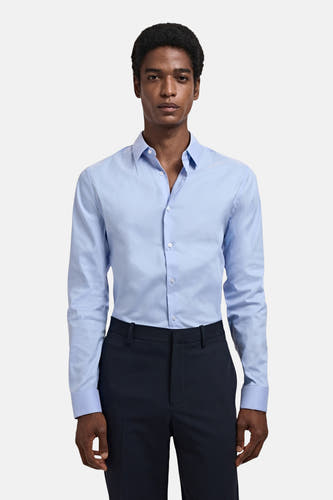 Chemise bleue à manches longues de MANGO, portée avec un pantalon foncé.