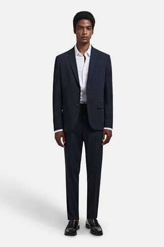 Wit overhemd met lange mouwen van MANGO, gedragen met een donkerblauw pak en zwarte schoenen.