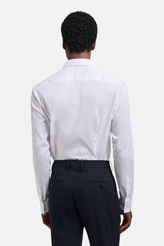 Wit overhemd met lange mouwen van MANGO, gezien van achteren, gecombineerd met een donkere pantalon.
