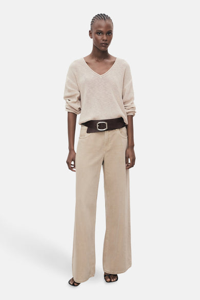Gilet beige à col V de MANGO, avec des manches longues, associé à une ceinture brune et à un pantalon large.