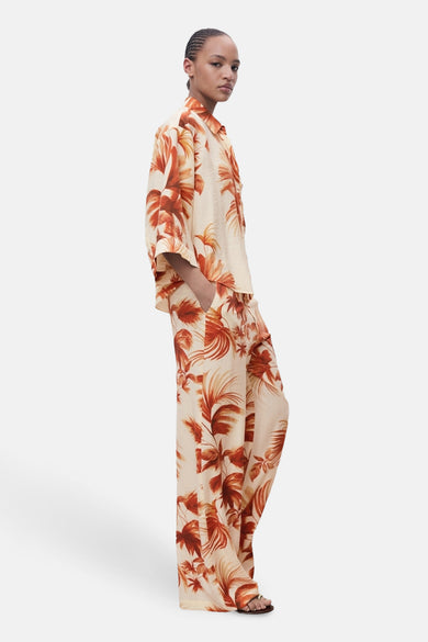 Pantalon multicolore de MANGO, avec un motif de feuille tropicale et des jambes larges, montré en vue latérale.