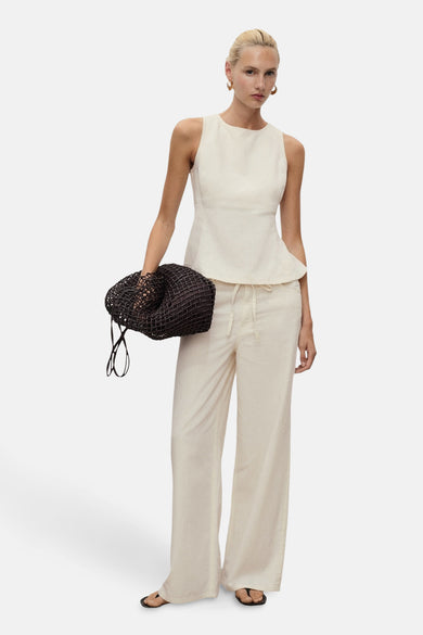 Ecru mouwloze blouse van MANGO, met een peplum silhouet en gecombineerd met crèmekleurige, wijde broek en zwarte sandalen.