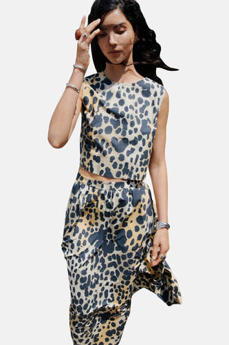 Beige mouwloze blouse van MANGO met luipaardprint, gecombineerd met een bijpassende rok en zilveren armbanden.
