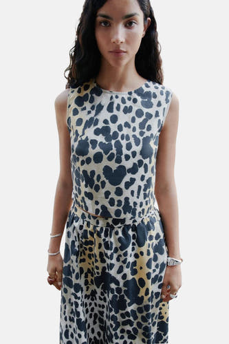 Beige mouwloze blouse van MANGO, met een zwart gevlekte print en gedragen met een bijpassende rok.
