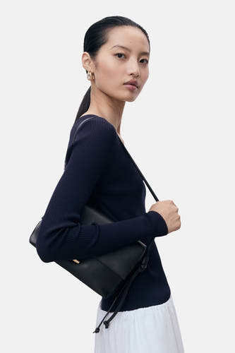 T-shirt bleu avec col rond de MANGO, en texture côtelée et longues manches, porté avec un sac noir.