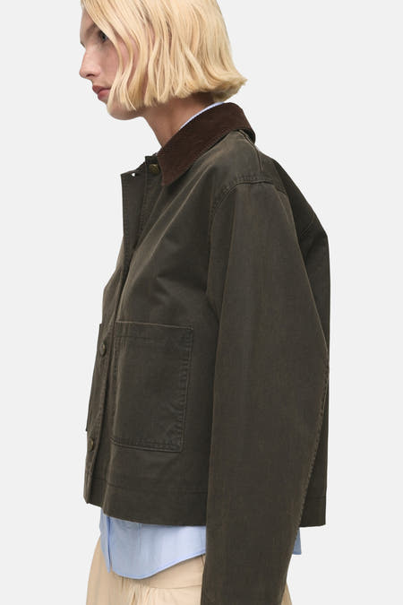 Khaki korte jas van MANGO, met bruine kraag en een zichtbaar blauw overhemd eronder, in zijaanzicht.
