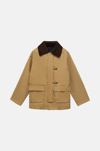 Beige korte jas van MANGO, met een bruine kraag en opgestikte zakken aan de voorkant.