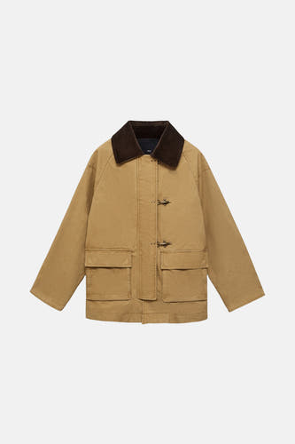 Beige korte jas van MANGO, met bruine kraag en zakken aan de voorkant.