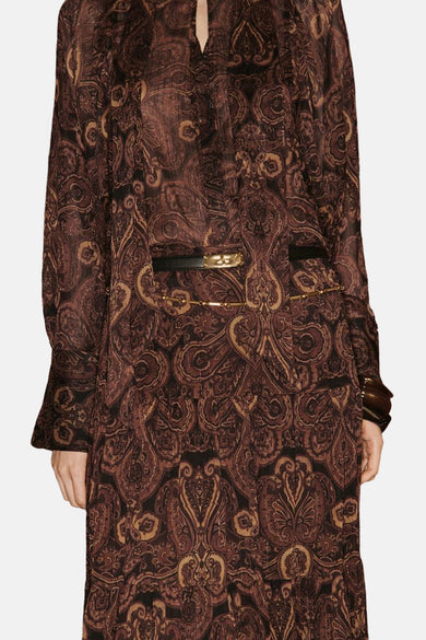 Long manteau brun de MANGO, avec une impression paisley et une ceinture noire avec des détails dorés.