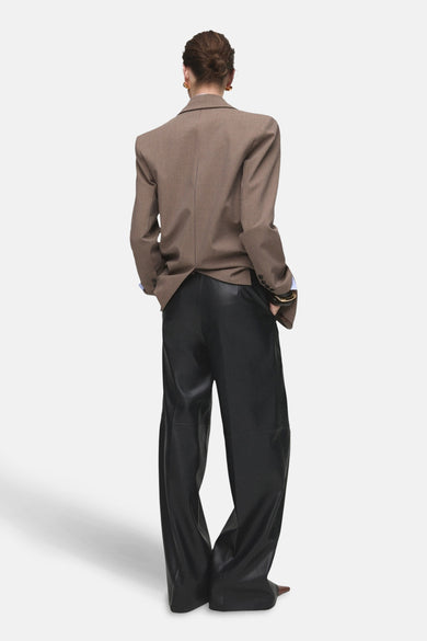 Pantalon de costume noir MANGO, avec des jambes larges et une texture lisse, vu de derrière.