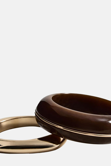 Gouden armband van Mango, naast een bruine armband met een gouden rand.
