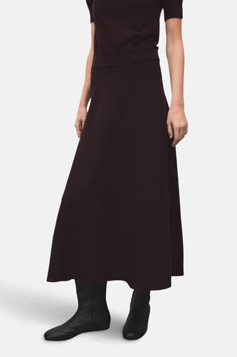 Lange bordeaux rok van MANGO, met een gladde textuur en gecombineerd met zwarte laarsjes.