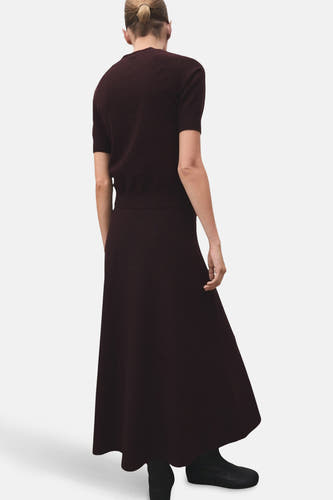 Lange bordeaux rok van MANGO, gezien van achteren, met een effen ontwerp en een vloeiende textuur.
