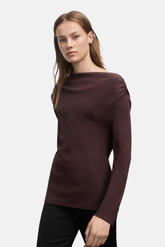 Bruine blouse met lange mouwen van MANGO, met een gedrapeerd detail op de schouder en gecombineerd met een zwarte broek.
