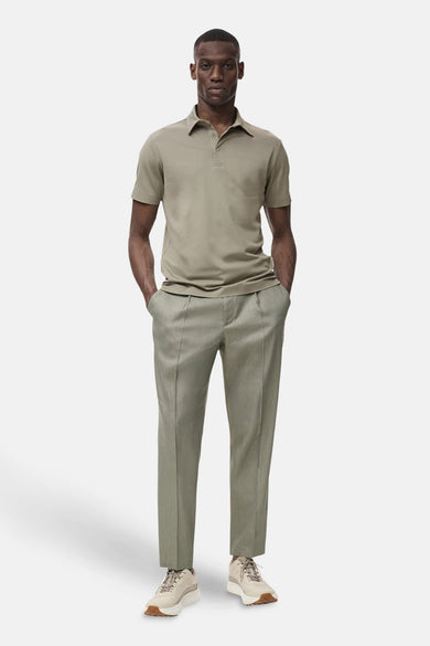 Kaki polo avec des manches courtes de MANGO, associé à un pantalon vert et des baskets beige.
