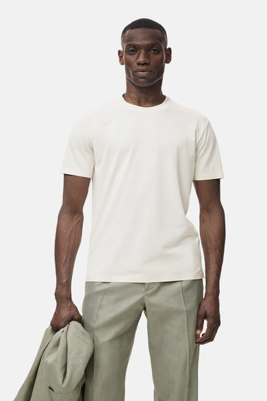 T-shirt écru à manches courtes de MANGO, associé à un pantalon vert et à un blouson coordonné.