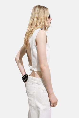 Ecru blouse zonder mouwen van MANGO, met open rug en geknoopt detail, gecombineerd met een witte jeans.