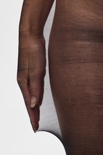 Pantys noirs de PIECES®, gros plan d'une main qui tire la panty contre un fond blanc.