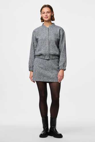 Pantys noirs de PIECES®, portés avec une jupe et un manteau en tweed gris, et des bottes noires.